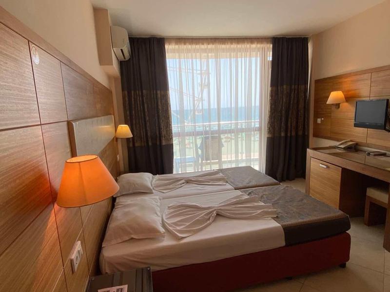 Modern hotel room with double bed, desk, TV, and sea view.