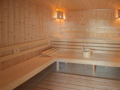 Lichte sauna met houten betegeling, banken en een emmer met lepeltje.