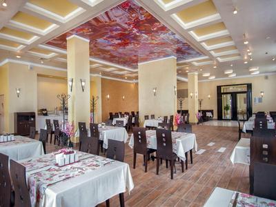 Elegant hotelrestaurant met witte tafelkleden en versierd plafondmuur.