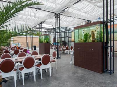 Modern overdekt restaurant met witte tafels, bruine stoelen en planten