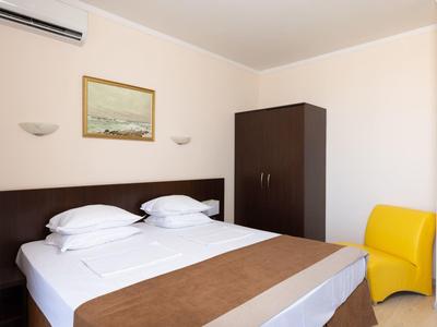 Een eenvoudig ingericht hotelkamer met tweepersoonsbed, kleine kast en gele stoel.