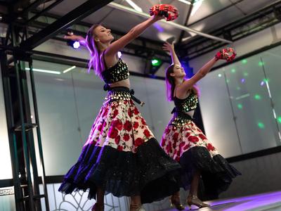 Twee dansers in kleurrijke kostuums voeren een traditionele dans uit op een podium.