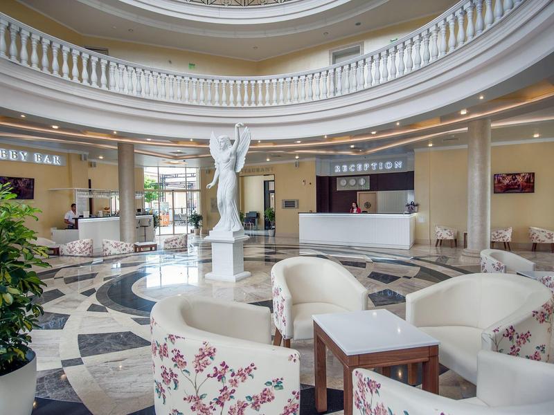 Elegante hotellobby met zuilen, marmeren vloeren en comfortabele zitgedeeltes met bloemenpatroon stoelen.