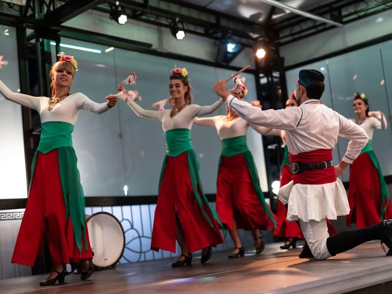 Dansers in traditionele kleding voeren een uitvoering uit op een binnenpodium.