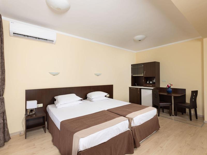 Hotelkamer met twee eenpersoonsbedden, bureau, magnetron en airconditioning.