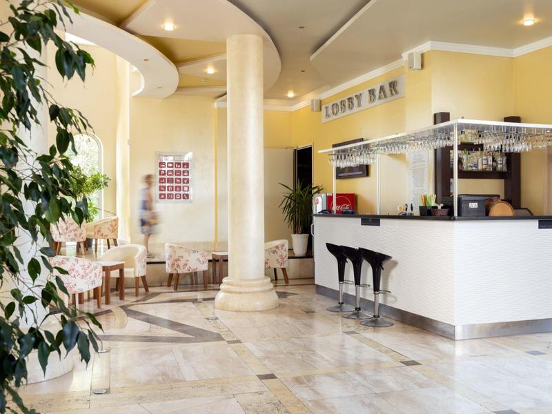 Heldere hotel lobby met bar, zithoek en marmeren vloer.