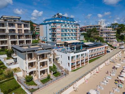 Strand mit Reihen von weißen Liegestühlen neben modernen mehrstöckigen Hotels unter blauem Himmel.