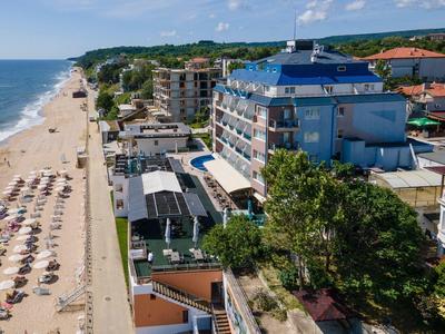 Strand mit Sonnenschirmen und Hotels an der Küste unter blauem Himmel.