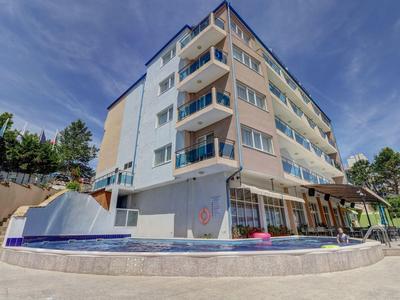 Mehrstöckiges Hotelgebäude mit Balkonen und kleinem Poolbereich bei sonnigem Himmel