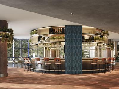 Modern round hotel bar area with wooden chairs and decorative plants.