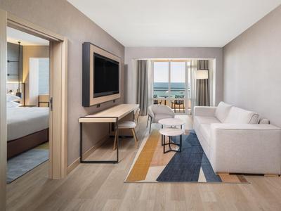 Modern eingerichtetes Wohnzimmer und Schlafzimmer mit Meerblick im Hotelzimmer.