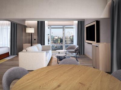 Modern hotel living area with sofa, armchair, cabinet, TV, and view of a terrace.