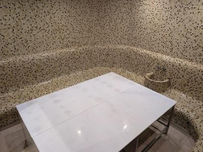 Moderner Essbereich mit weißem Tisch und gepolsterten, gemusterten Sitzbänken in einem Hotelzimmer.