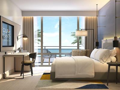 Modern hotel room with double bed, desk, balcony, and sea view.