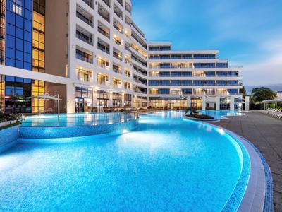 Modernes Hotel mit beleuchtetem Außenpool bei Dämmerung