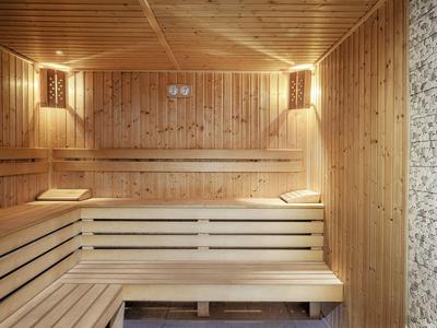 Holzsauna mit mehrstufigen Bänken und gedämpfter Beleuchtung an den Wänden.