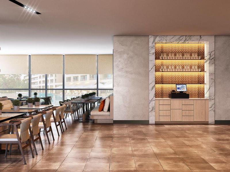 Modern hotel dining area with wooden floor, tables, chairs, and large windows with a view.