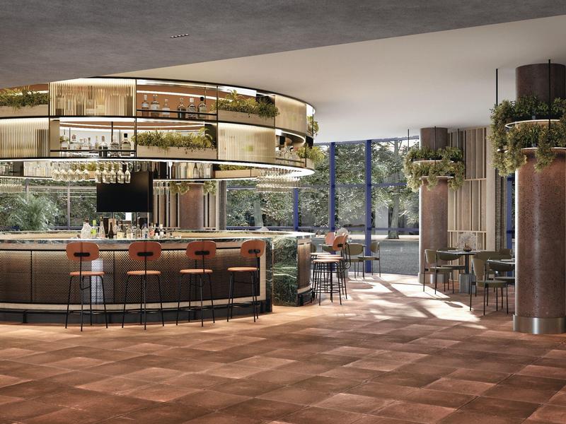 Modern hotel bar area with a round counter, bar stools, and plenty of natural light.