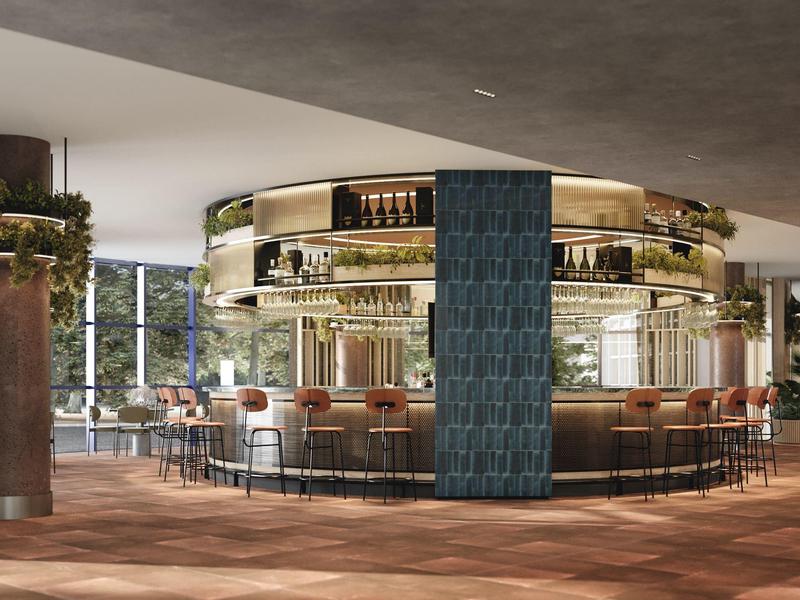 Modern round hotel bar area with wooden chairs and decorative plants.