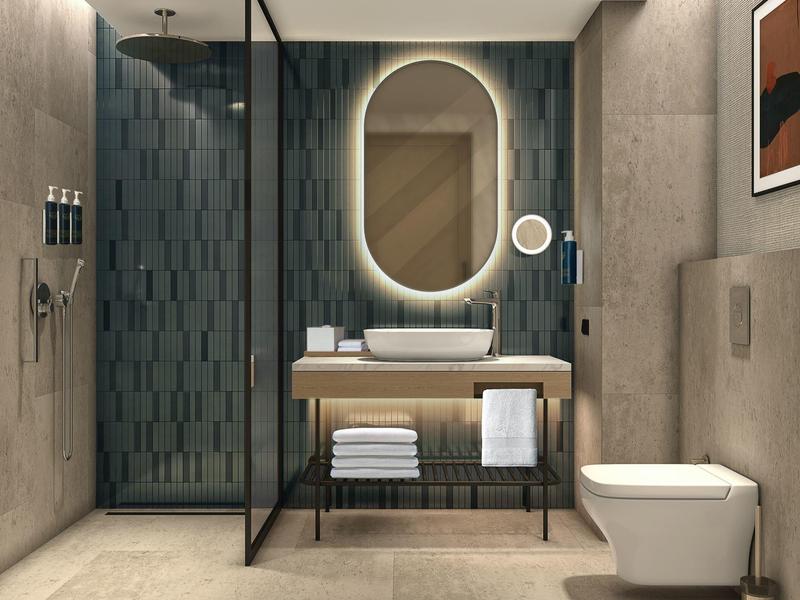 Modern bathroom with round illuminated mirror, freestanding sink, and walk-in shower.