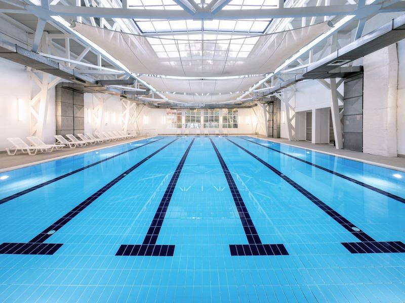 Large indoor swimming pool with multiple lanes and white walls.
