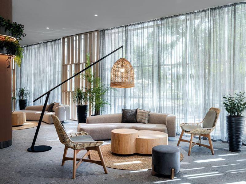 Modern hotel lounge with chairs, sofas, curtains, and natural lighting.
