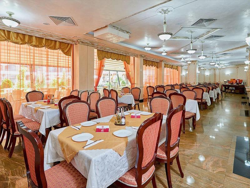 Großer Speisesaal mit rechteckigen Tischen, viktorianischen Stühlen und rosafarbenen Polstern.