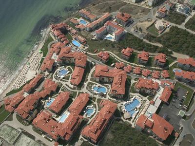 Widok z lotu ptaka na kompleks hotelowy z wieloma budynkami i basenami nad morzem.