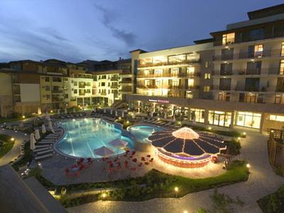 Modernes Hotel mit beleuchtetem Außenpool und Sonnenschirmen bei Abenddämmerung