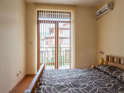 Eenvoudige slaapkamer met tweepersoonsbed, verticale jaloezieën en airconditioning.