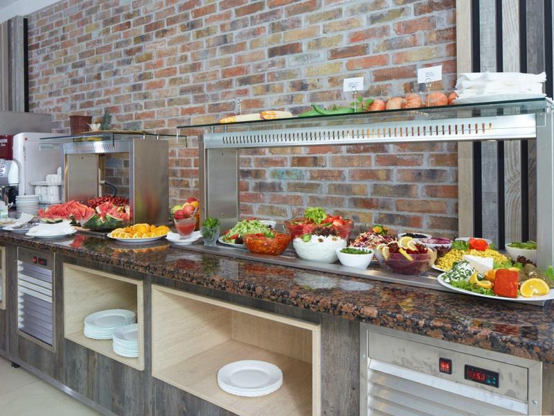 Buffet met verse groenten, salades en dressings in een moderne eetruimte.