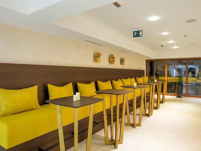 Area salotto moderna gialla con tavoli in legno e cuscini in un ristorante o hotel