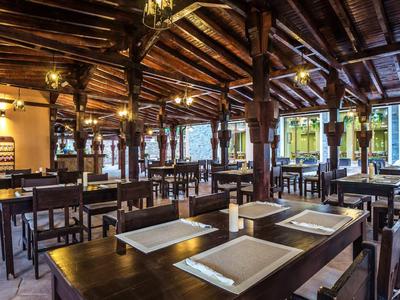 Ristorante d'hotel rustico con mobili in legno scuro e colonne decorative in legno sotto un soffitto in legno.