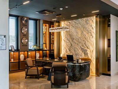 Moderner Hotel-Loungebereich mit stilvollen Sesseln und beleuchteter Steinwand.