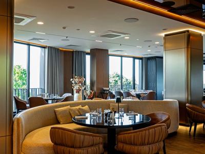 Moderner Lounge-Bereich mit runden Sofas und großen Fenstern mit Tageslicht.