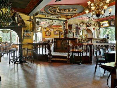 Gemütliches Restaurant mit Holzdecke, Kronleuchtern, runden Tischen und Bar im Zentrum.