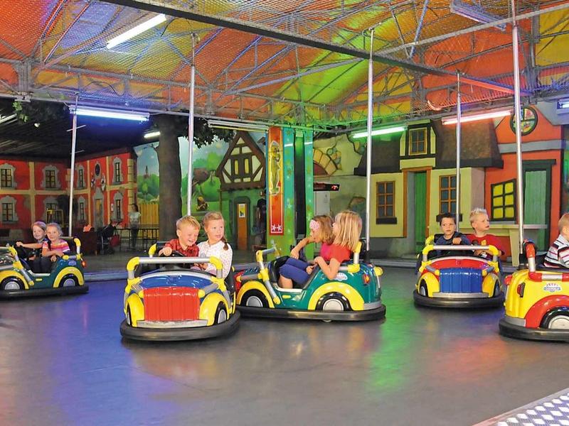 Mehrere Kinder fahren bunte Go-Karts in einer bunten, überdachten Halle mit Neonlichtern.