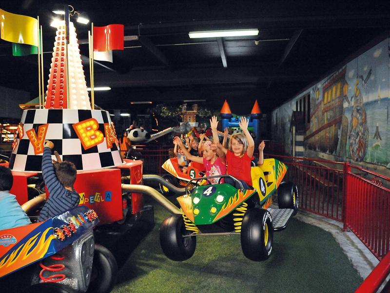 Kinder fahren mit bunten, leuchtenden Fahrgeschäften in einem Indoor-Vergnügungspark.