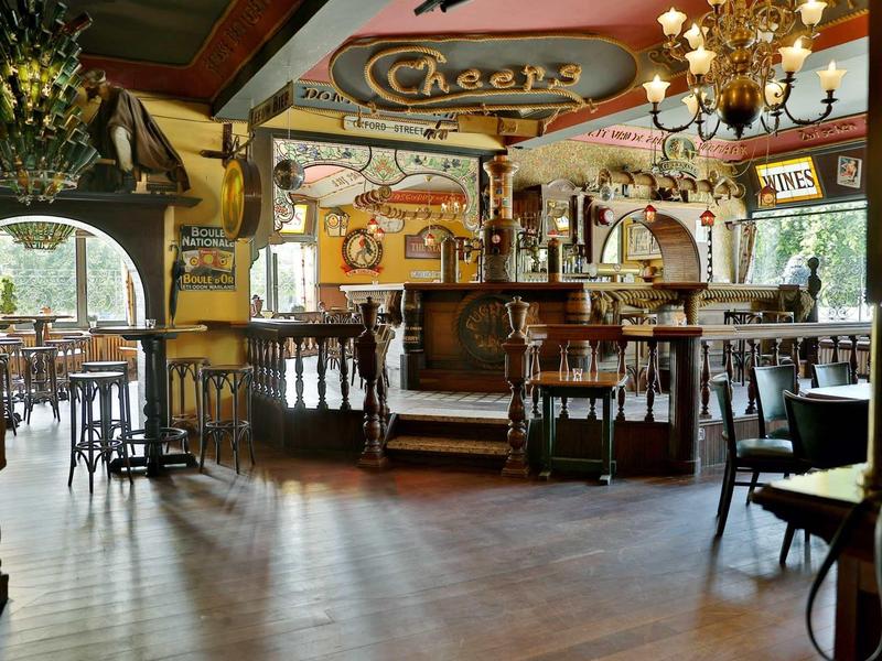 Gemütliches Restaurant mit Holzdecke, Kronleuchtern, runden Tischen und Bar im Zentrum.