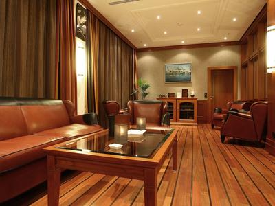 Gemütlicher Wohnraum mit braunen Ledersesseln, Holzboden und einem Glastisch in warmem Licht.