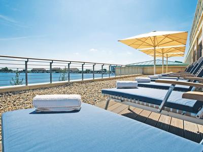 Liegestühle mit Handtüchern auf einer Dachterrasse mit Meerblick und blauem Himmel