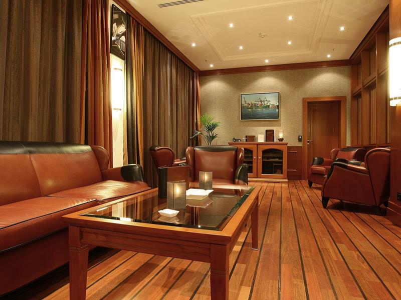 Gemütlicher Wohnraum mit braunen Ledersesseln, Holzboden und einem Glastisch in warmem Licht.