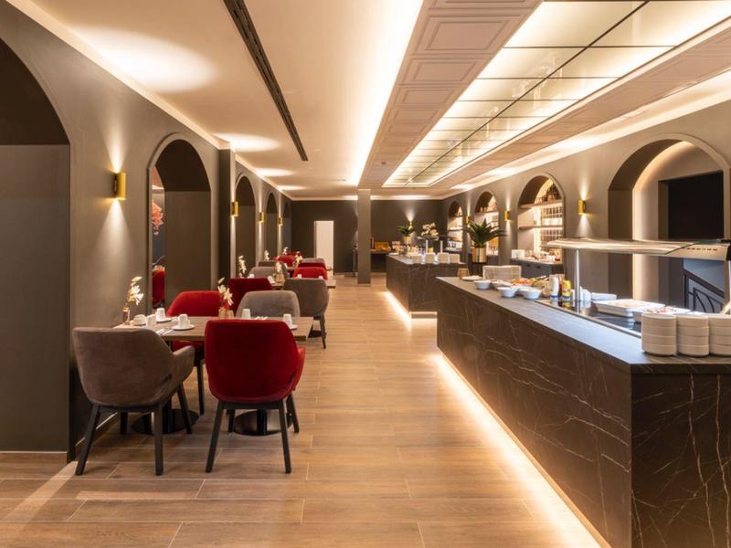 Modern hotel restaurant interior with warm lighting and elegantly set tables.