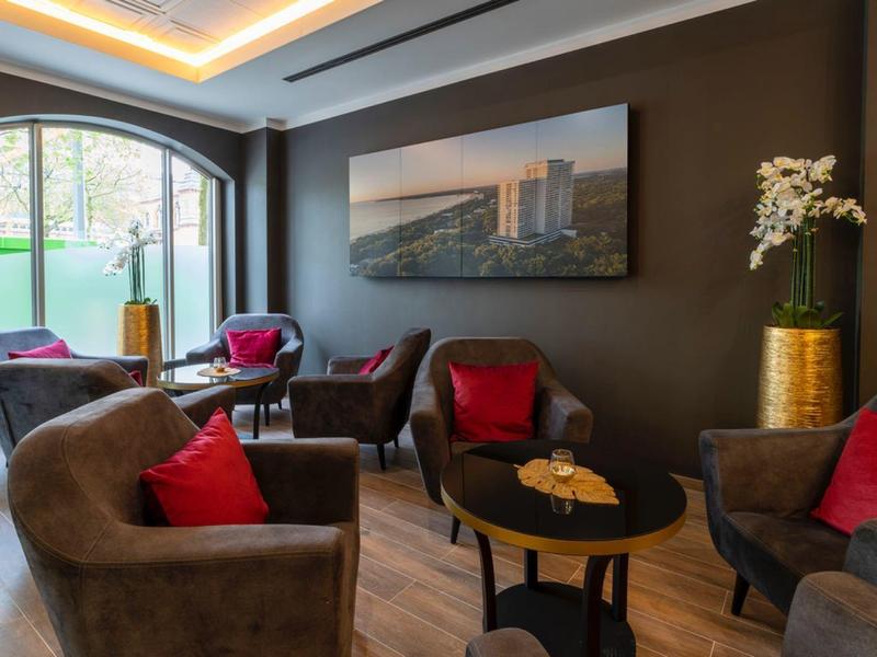 Cozy hotel lounge area with armchairs, red cushions, and a large window