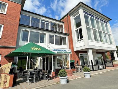 Außenansicht eines modernen Hotels mit Terrassenbestuhlung und Sonnenschirm.