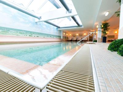 Piscine intérieure moderne avec grandes fenêtres et ambiance détendue dans un hôtel.