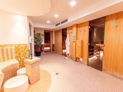 Espace bien-être moderne avec sauna en bois et zone de détente sous une lumière chaude.