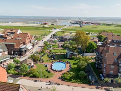 Blick von oben auf ein Hotel mit Pool, Garten und angrenzender Straße nahe der Küste.