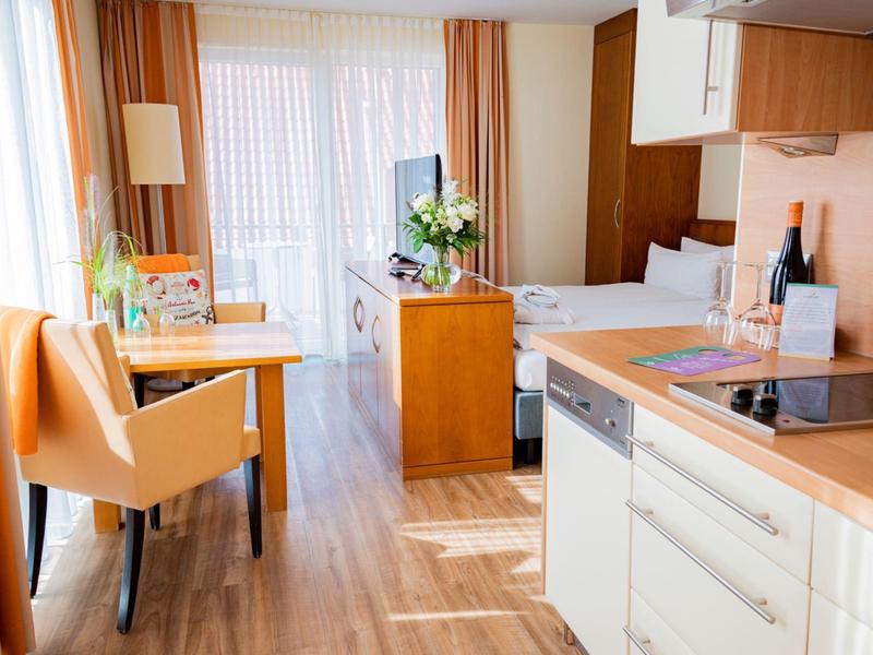 Coin cuisine lumineux avec plan de travail en bois, coin repas et porte patio avec rideaux