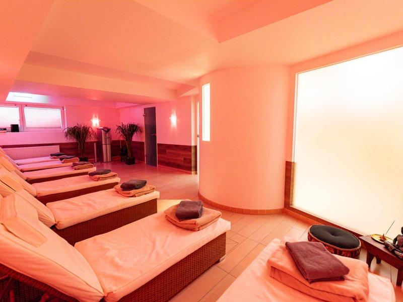 Salle de détente avec chaises longues et lumière rouge chaude dans un hôtel spa.